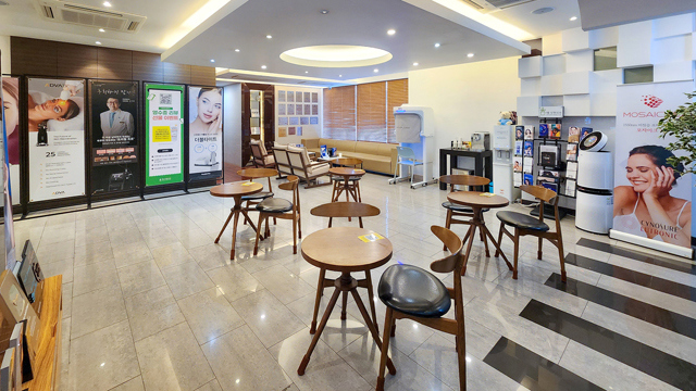 Waiting area at TAE Plastic Surgery Clinic with round tables, chairs, sofas, and treatment displays.