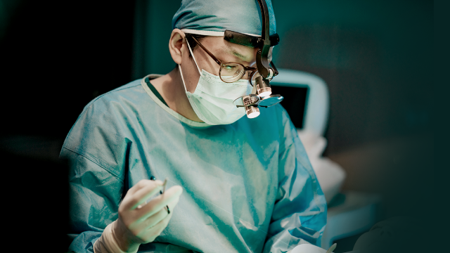 Plastic surgeon wearing surgical loupes performing breast lift procedure at TAE Plastic Surgery Clinic.