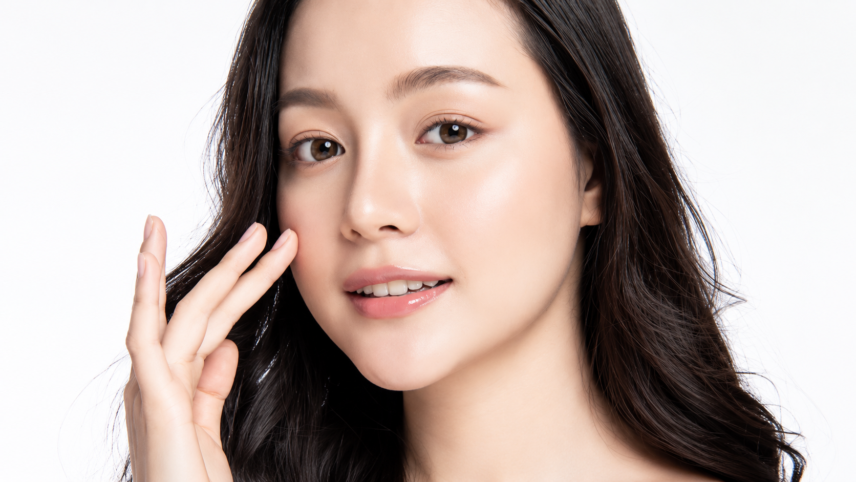 Woman with long dark hair gently touching her cheek below the eye, illustrating under-eye fat correction in Busan, Korea
