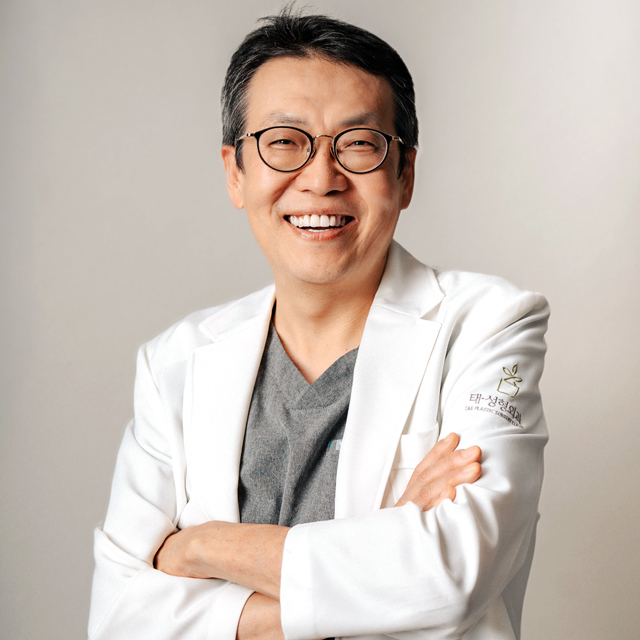 Dr. Kim Ki-tae, Board-Certified Plastic Surgeon at TAE Plastic Surgery Clinic, smiling with his arms crossed in a white coat.