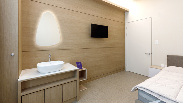 Patient room at Seoulhoho Hospital with a bed, sink, illuminated mirror, and wall-mounted television.