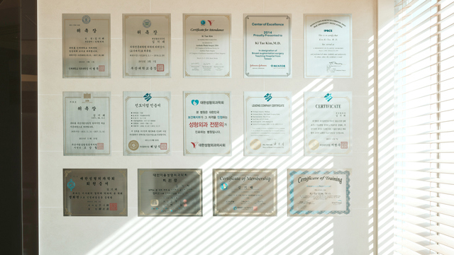 Wall display of professional certificates and training credentials at TAE Plastic Surgery Clinic.