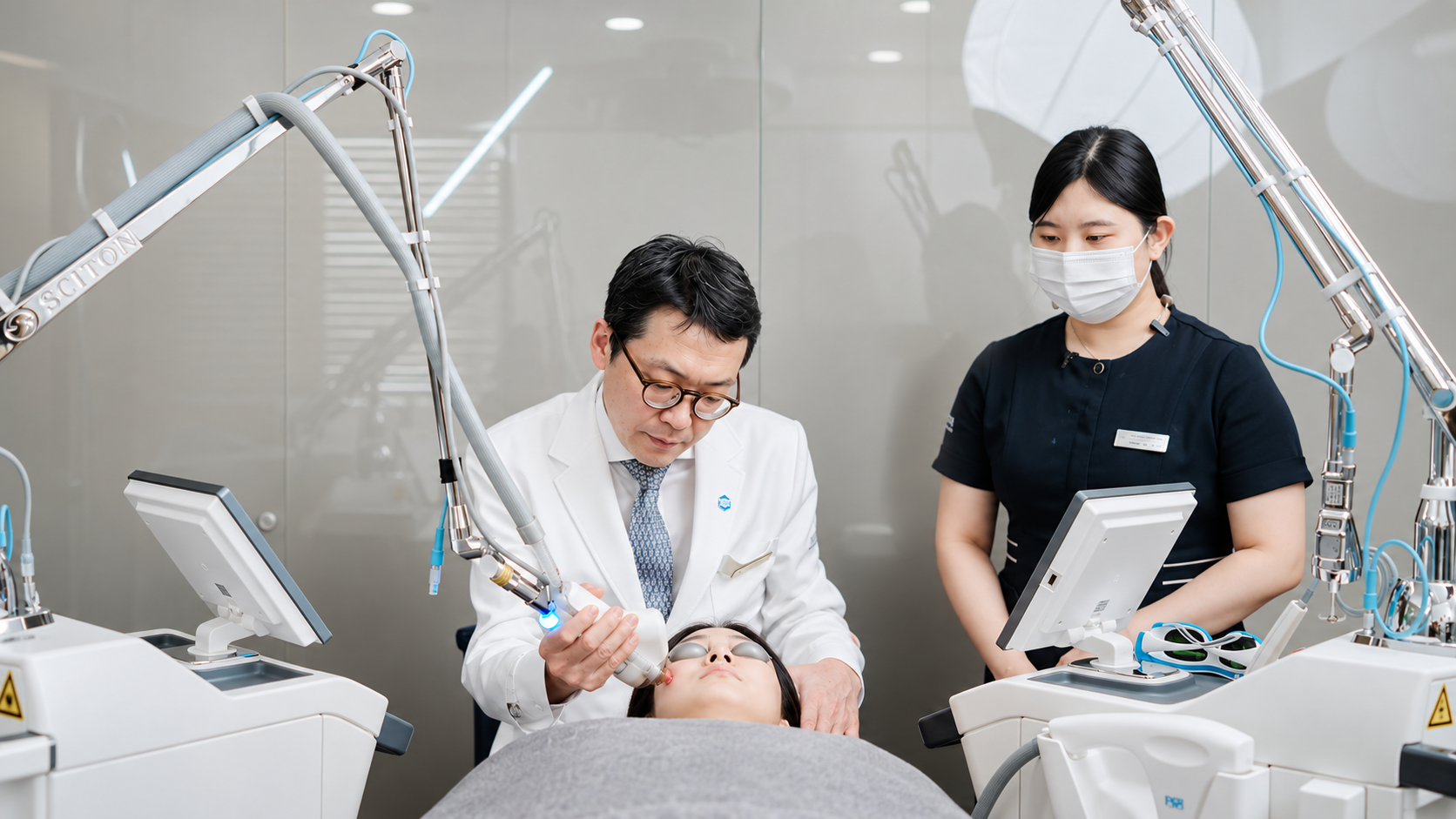 Medical aesthetic doctor performing laser facial rejuvenation on a patient accompanied by a clinical assistant in an advanced procedure room.