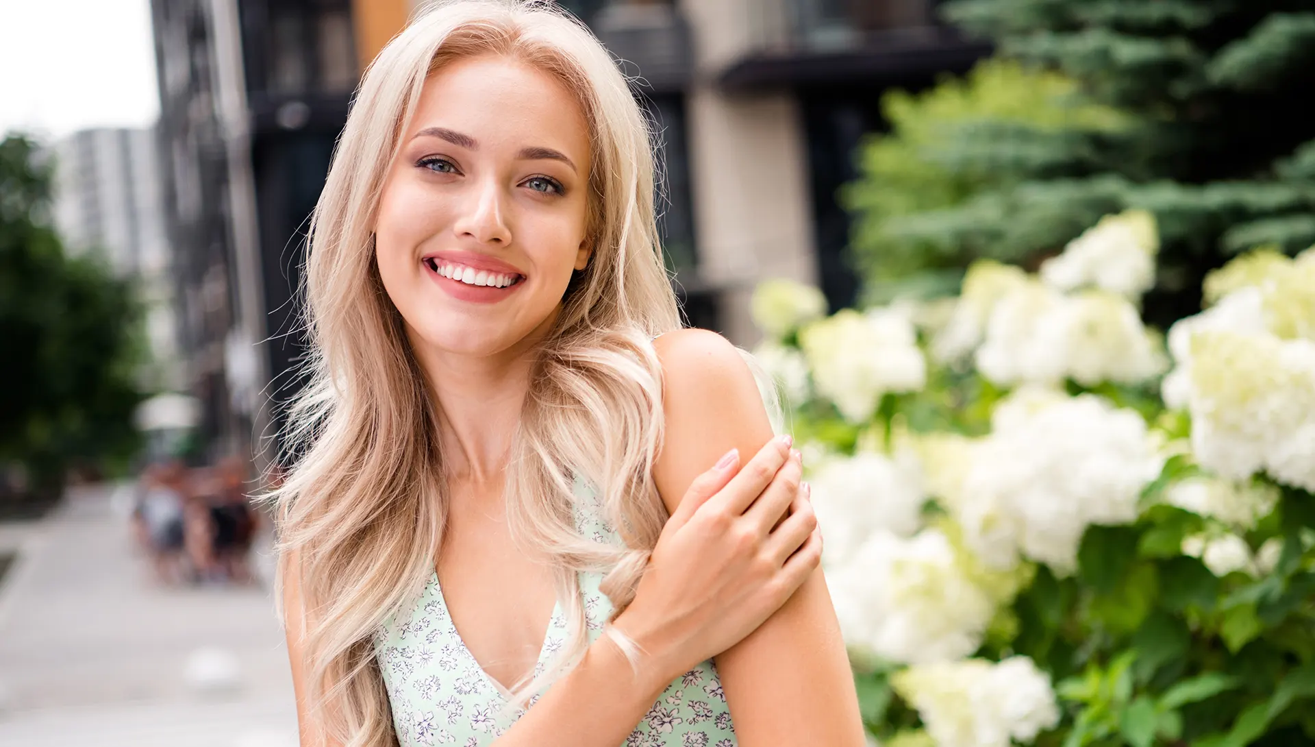 A smiling woman outdoors with a healthy, refreshed appearance, representing the systemic wellness benefits of nutritional IV therapy, including improved energy, hydration, and overall vitality.