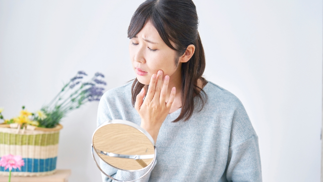 Woman examining facial swelling and redness in a mirror