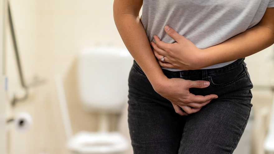 Woman holding lower abdomen experiencing discomfort related to chronic inflammatory conditions treatment