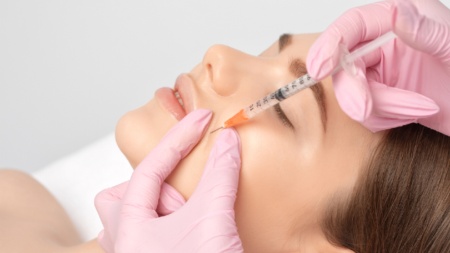 Doctor administering facial contouring filler injection near a patient's cheekbone
