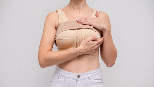 Woman wearing a supportive surgical bra during recovery after breast surgery.