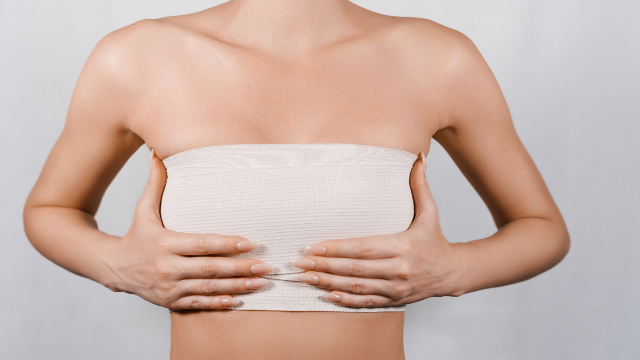 Woman holding her chest while recovering after breast augmentation surgery.