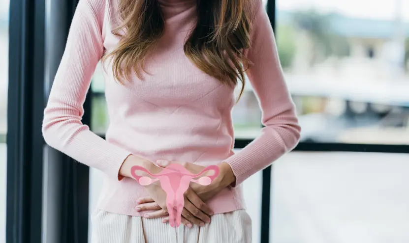 Woman holding lower abdomen with illustrated uterus symbol representing sexual and reproductive health care at an STD clinic